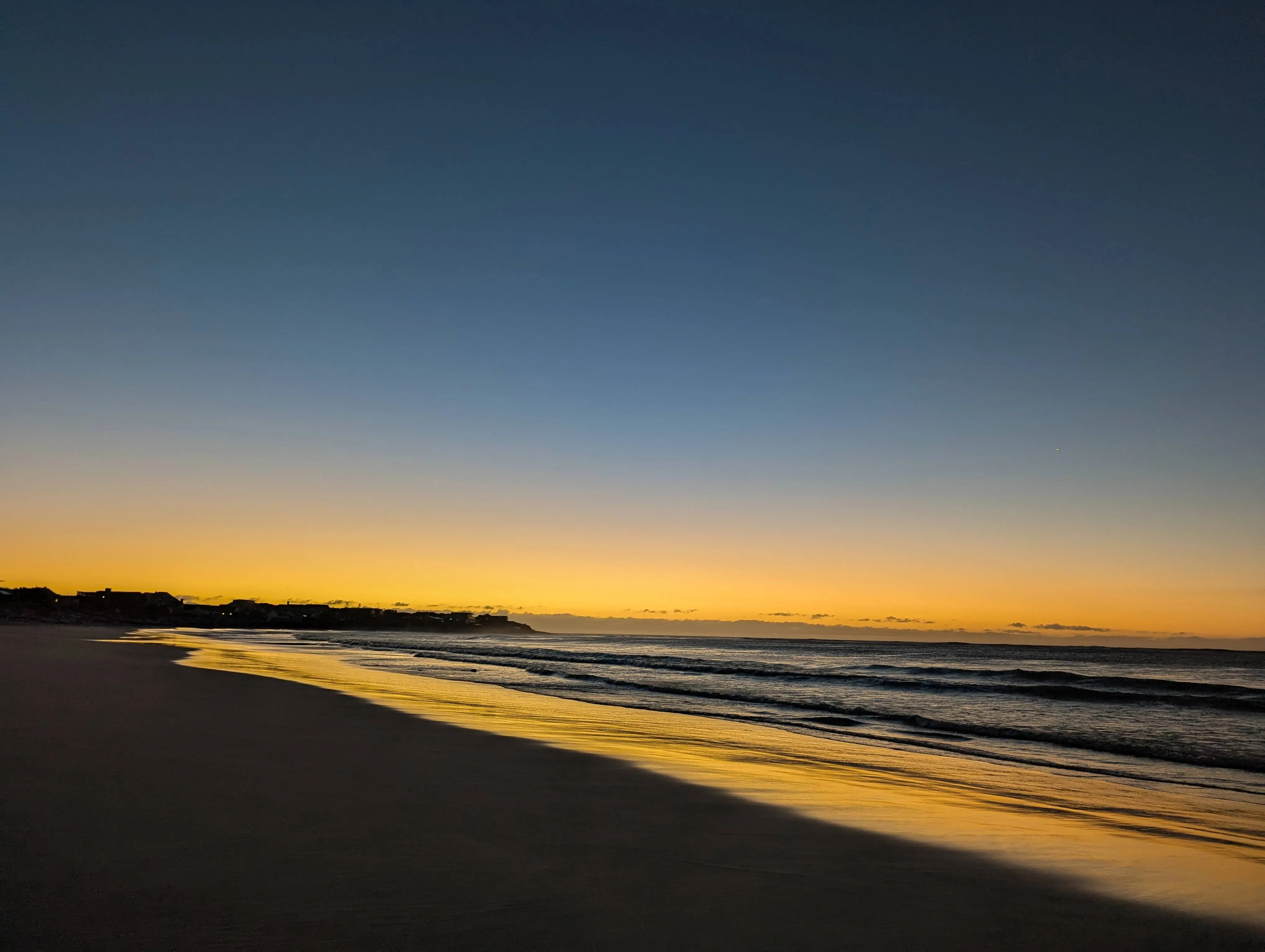 Magical Kommetjie sunset—glowing sky mirrored on wet sand.